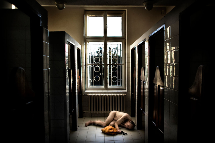 Mężczyzna leżący w łazience ośrodka dla Chorych Umysłowo w Szczytnej, fot. Adam Lach.